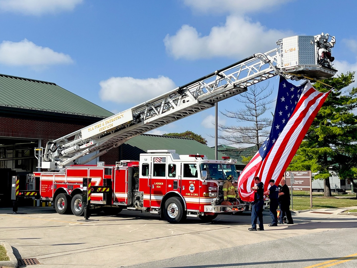 Firefighters prepare a flag to raise from a ladder truck.