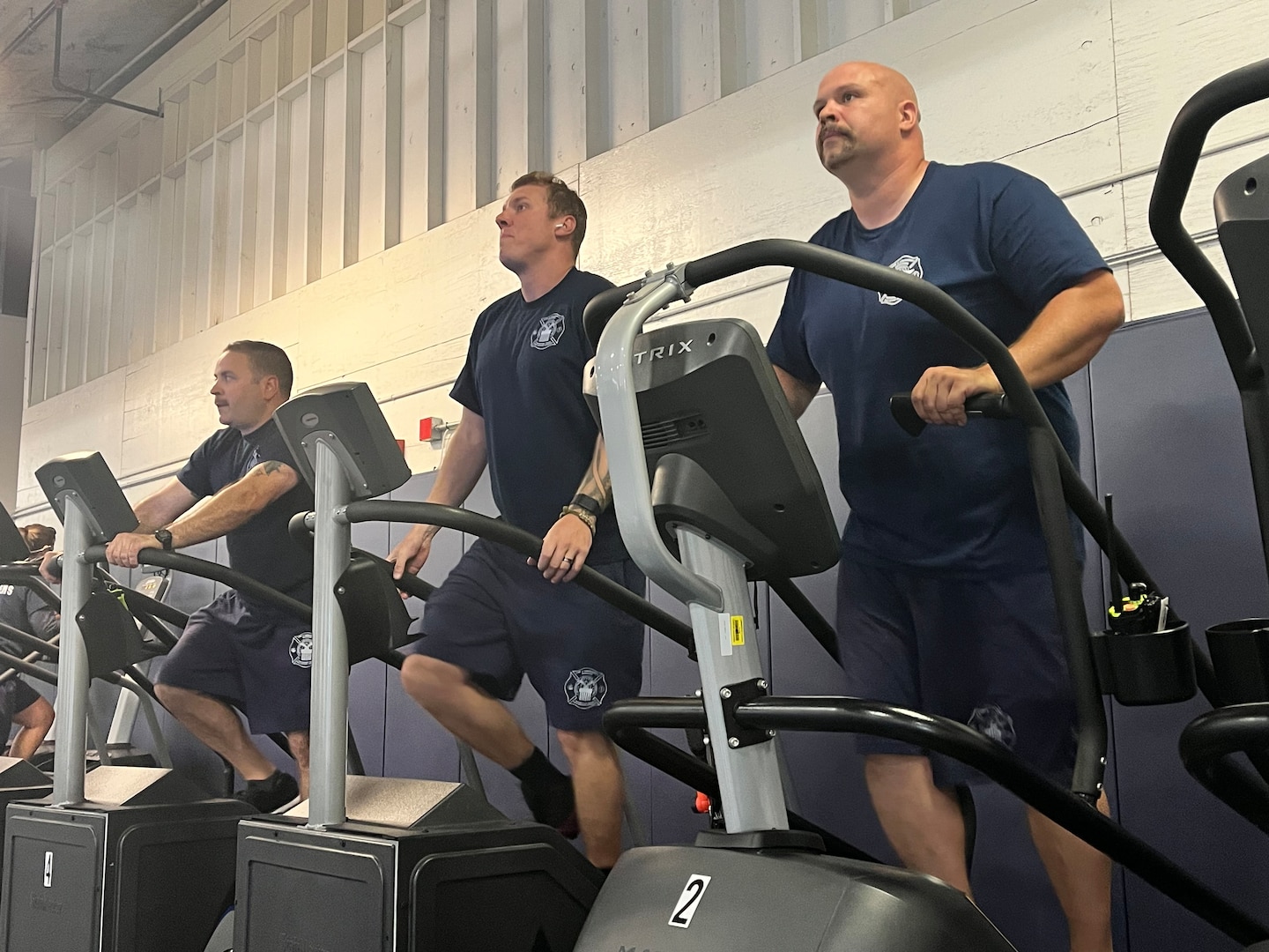 Three men work out on stair machines.