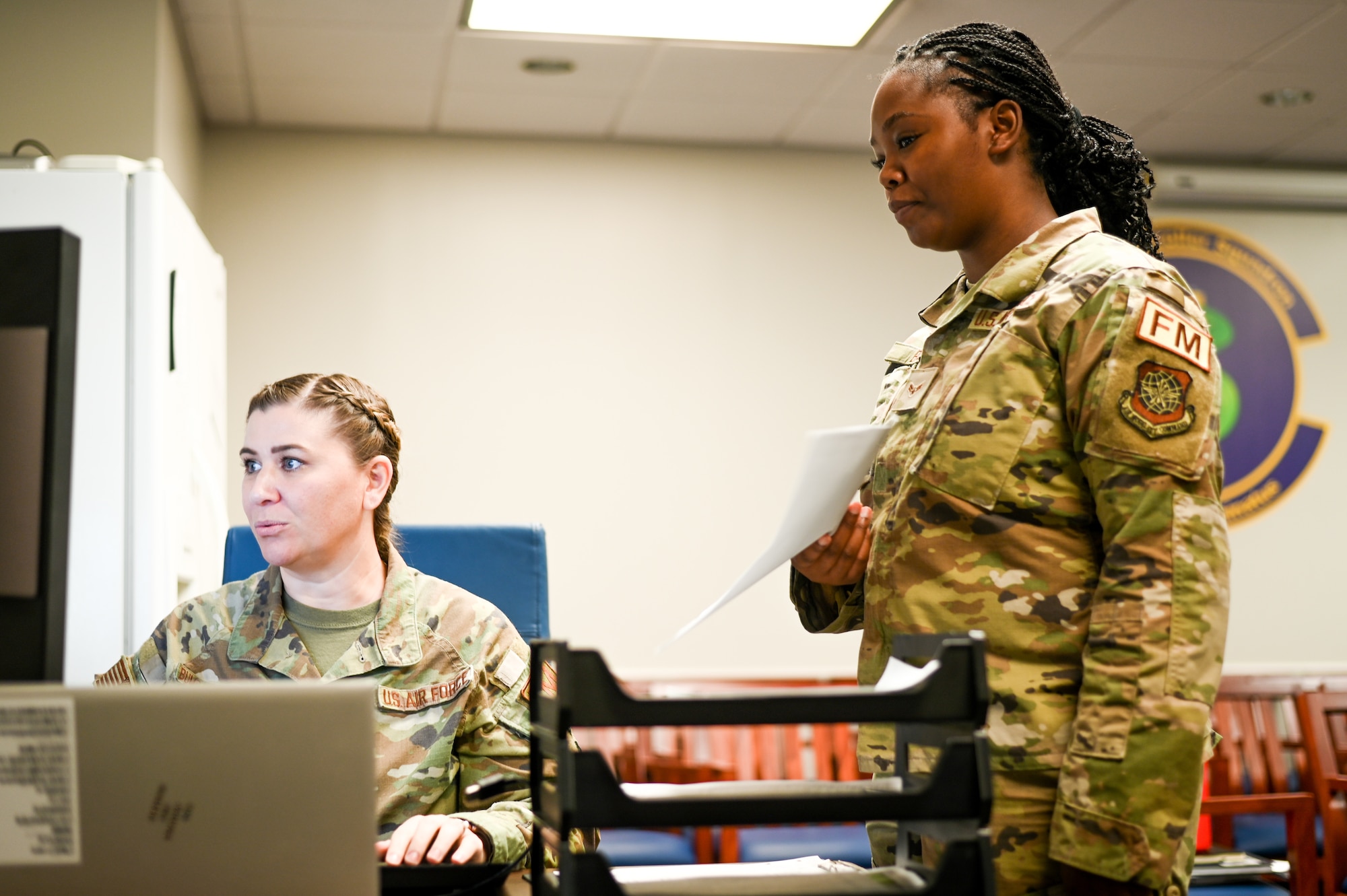 U.S. Air Force Staff Sgt. Ashley Bumgardner-Gaines, 6th Comptroller Squadron financial operations supervisor, assists Airman 1st Class Kori Barr, 6th CPTS financial services technician, with processing vouchers on MacDill Air Force Base on Sept. 8, 2023.