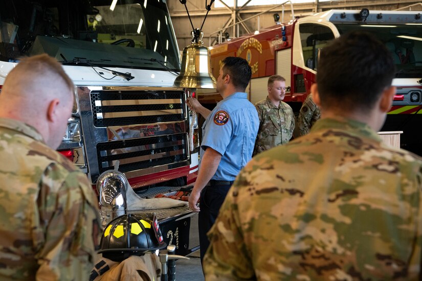 Members of the 628th Civil Engineer Squadron fire department ring a memorial bell during a ceremony.