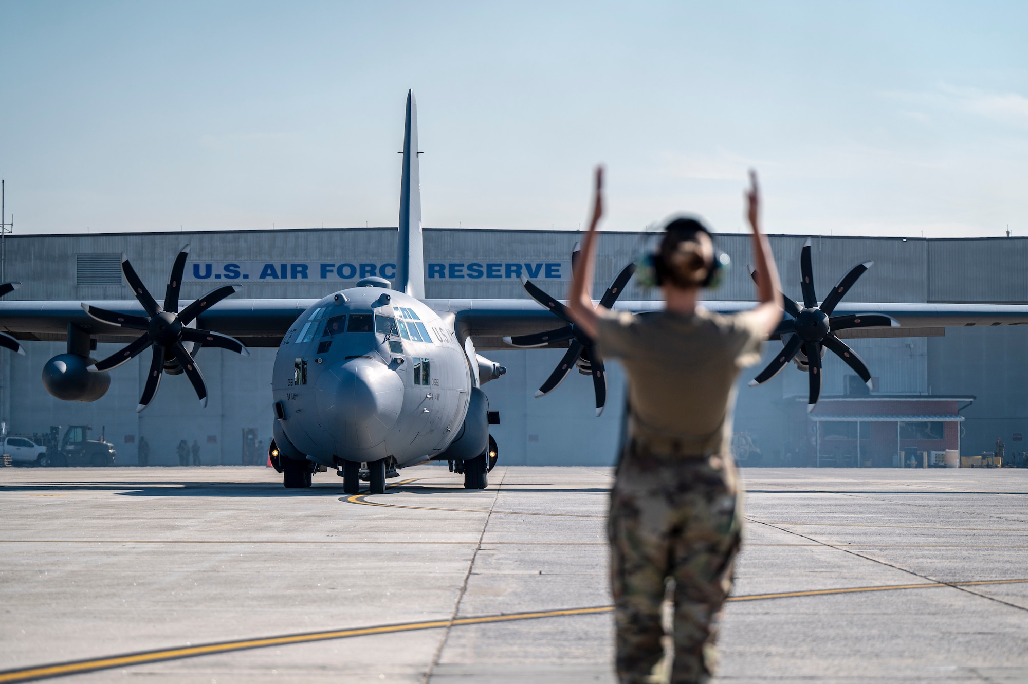 A woman stands with her arms up in front of a C-130H3 at the flight line on Dobbins Air Reserve Base, Ga.
