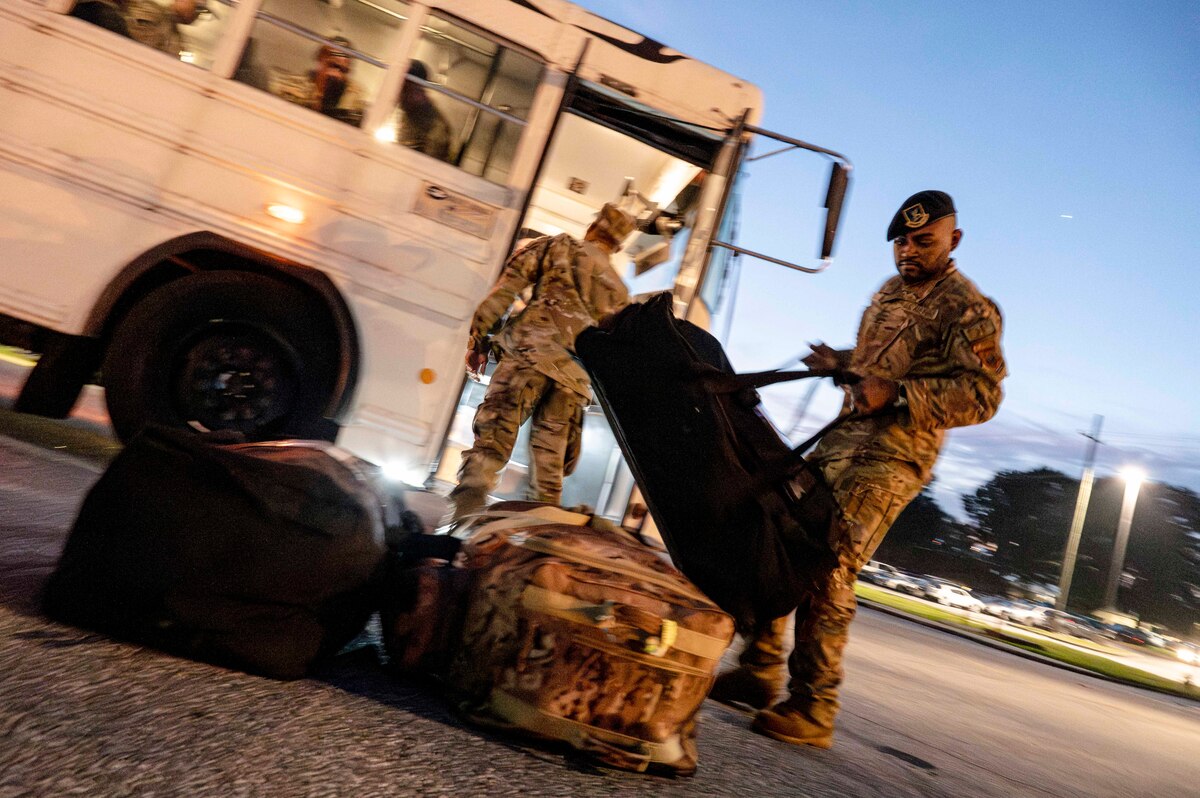 Man removes luggage from bus and places it on the ground.