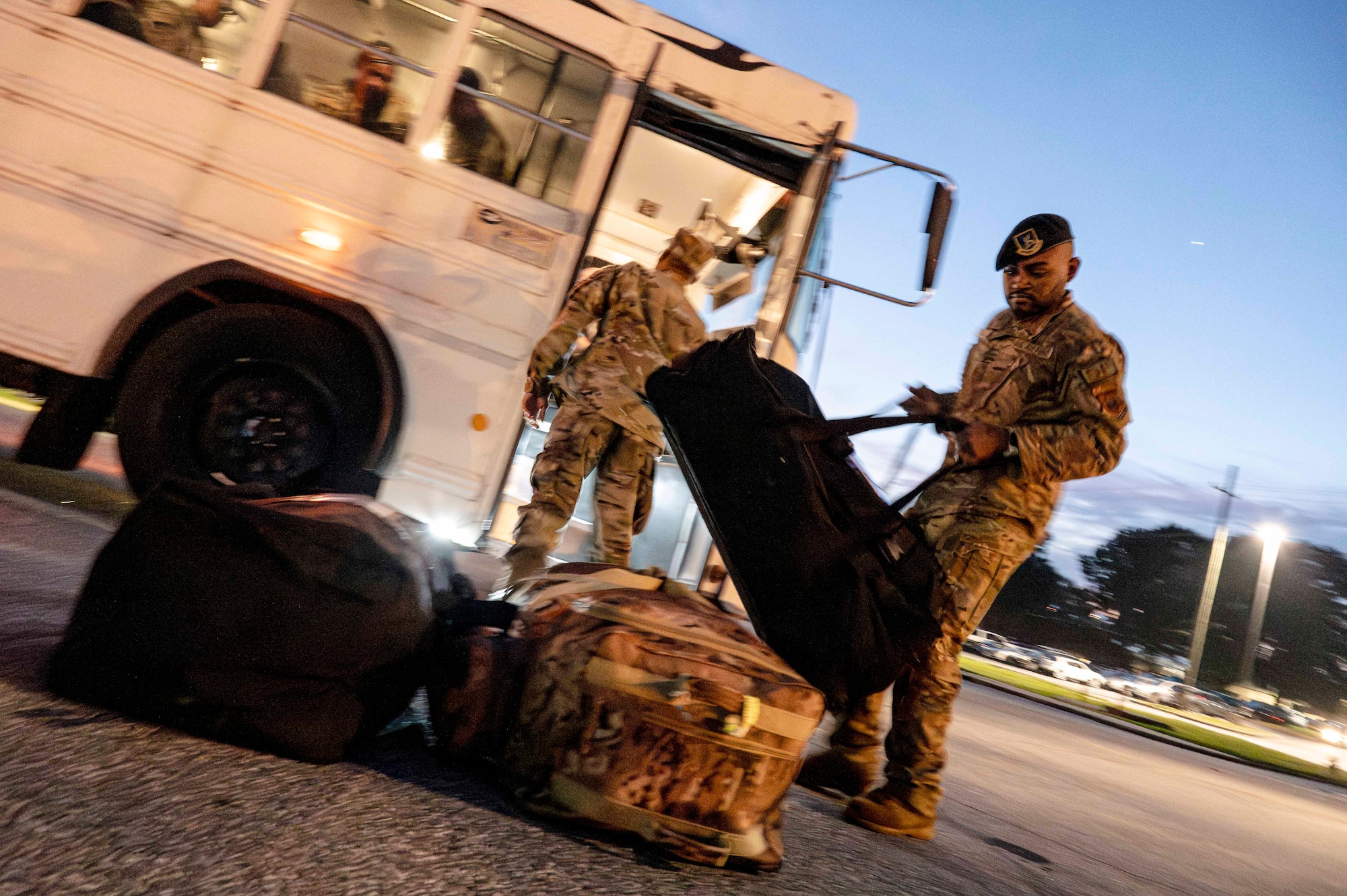 Man removes luggage from bus and places it on the ground.