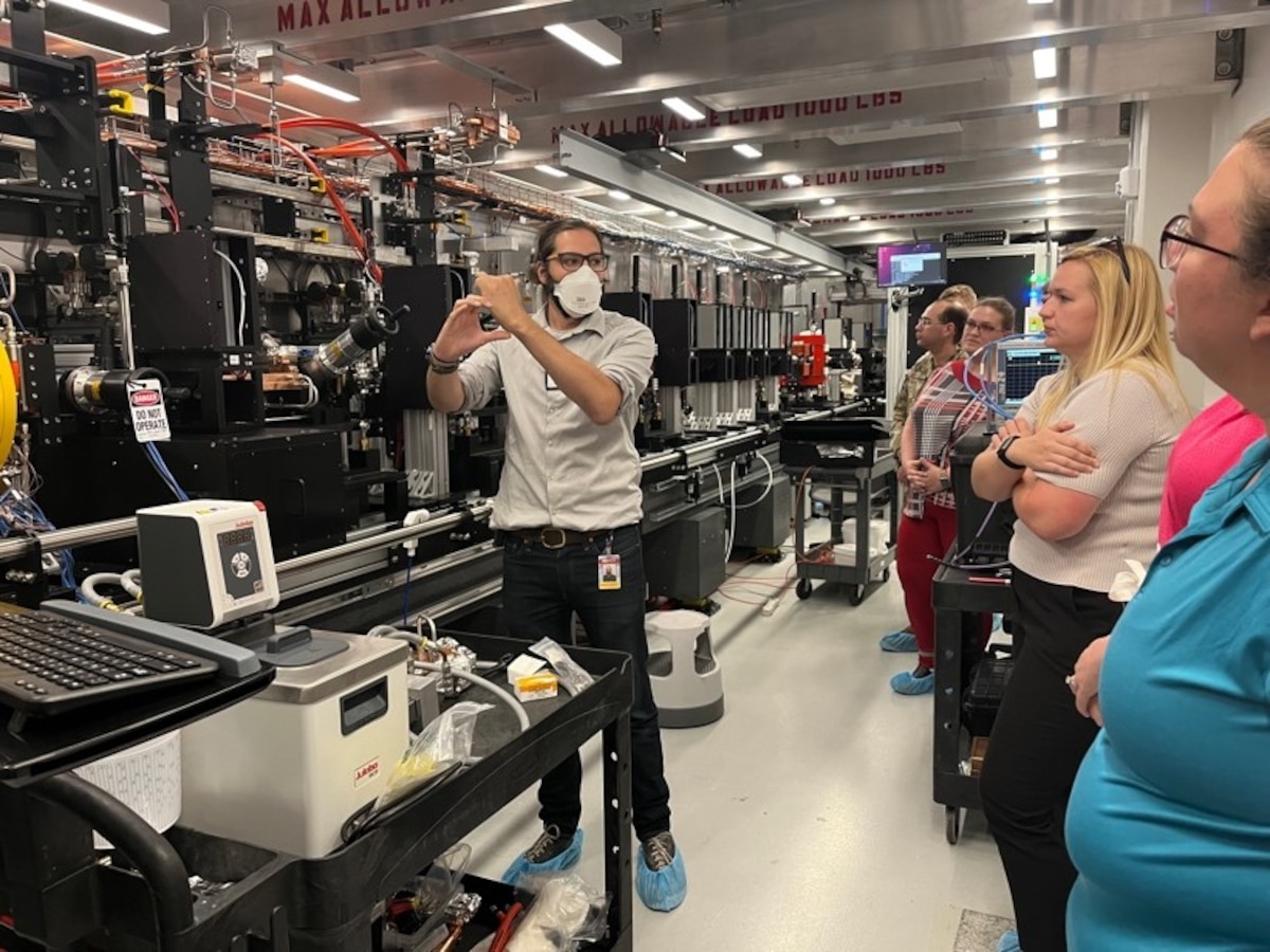 Dr. Samuel Teitelbaum, left, Arizona State University Assistant, or ASU, professor, shows Junior Force Council members the large-scale Compact X-Ray Free Electron Laser during a tour of ASU labs Aug. 10, 2023, part of the Air Force Research Laboratory JFC Bluing Trip at Luke Air Force Base, Ariz. In addition to touring the base to get an understanding of missions and organizations that support the Air Force, JFC members toured ASU to deepen their understanding of support and collaboration between industry and the DOD. (U.S. Air Force photo / Kiara Palmer)