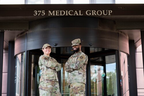 Two Airmen pose in front of "375 Medical Group" sign.