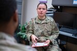 A women in the Air Force speaks to other Airmen while holding clipboard.