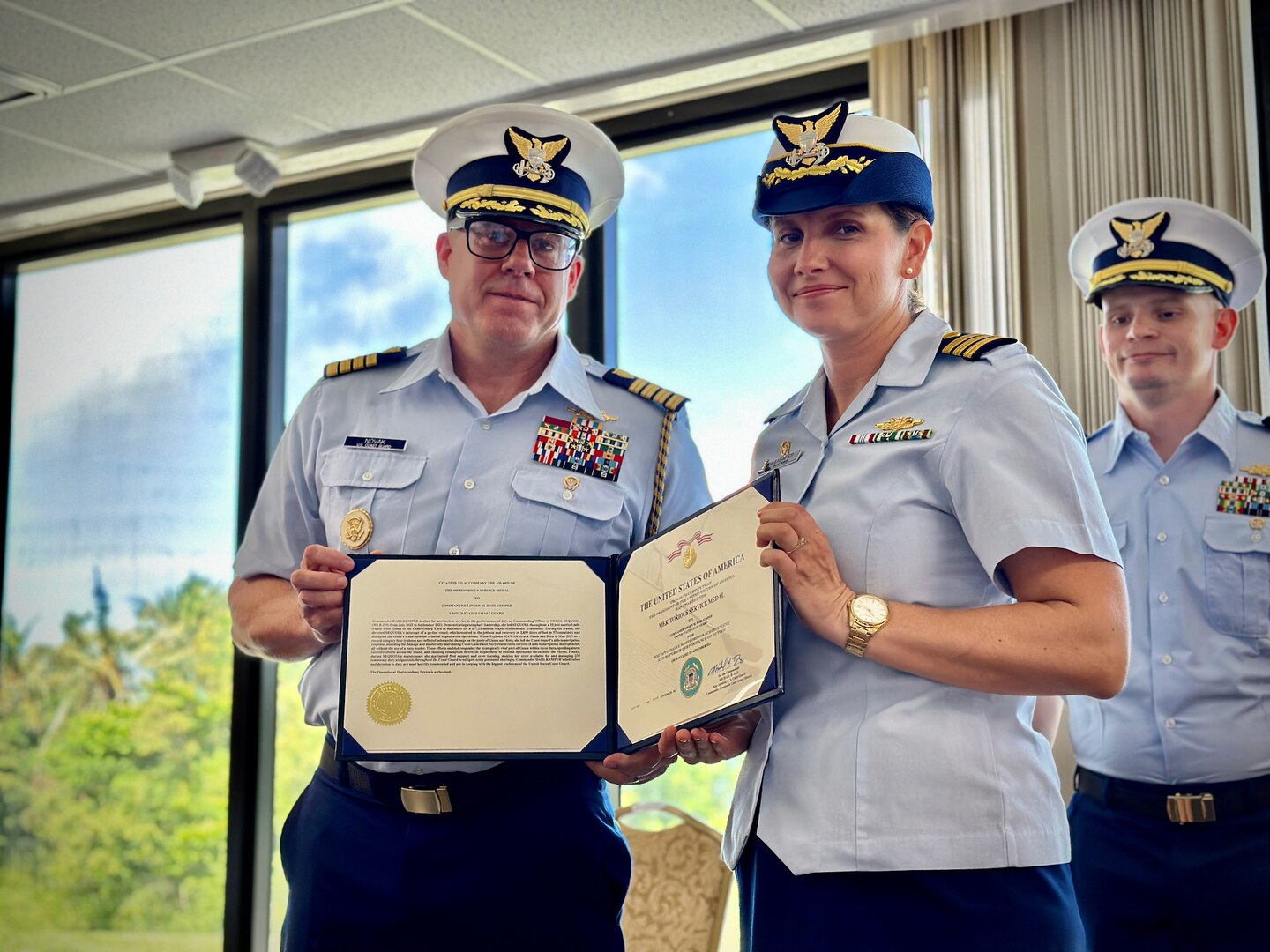 Capt. Blake Novak, chief of staff U.S. Coast Guard 14th District, presents Cmdr. Linden Dahlkemper with a U.S. Coast Guard Meritorious Service Medal for her work aboard USCGC Sequoia (WLB 215) during a change of command ceremony held at the Top o’the Mar in Guam on Wednesday, Sep. 13, 2023. The ceremony also signaled the official shift of the 225-foot seagoing buoy tender in Guam from USCGC Sequoia (WLB 215), currently at its major maintenance availability (MMA) at the U.S. Coast Guard Yard in Baltimore, to USCGC Hickory, which is just completing MMA and will now serve the Western Pacific. (U.S. Coast Guard photo by Chief Warrant Officer Sara Muir)