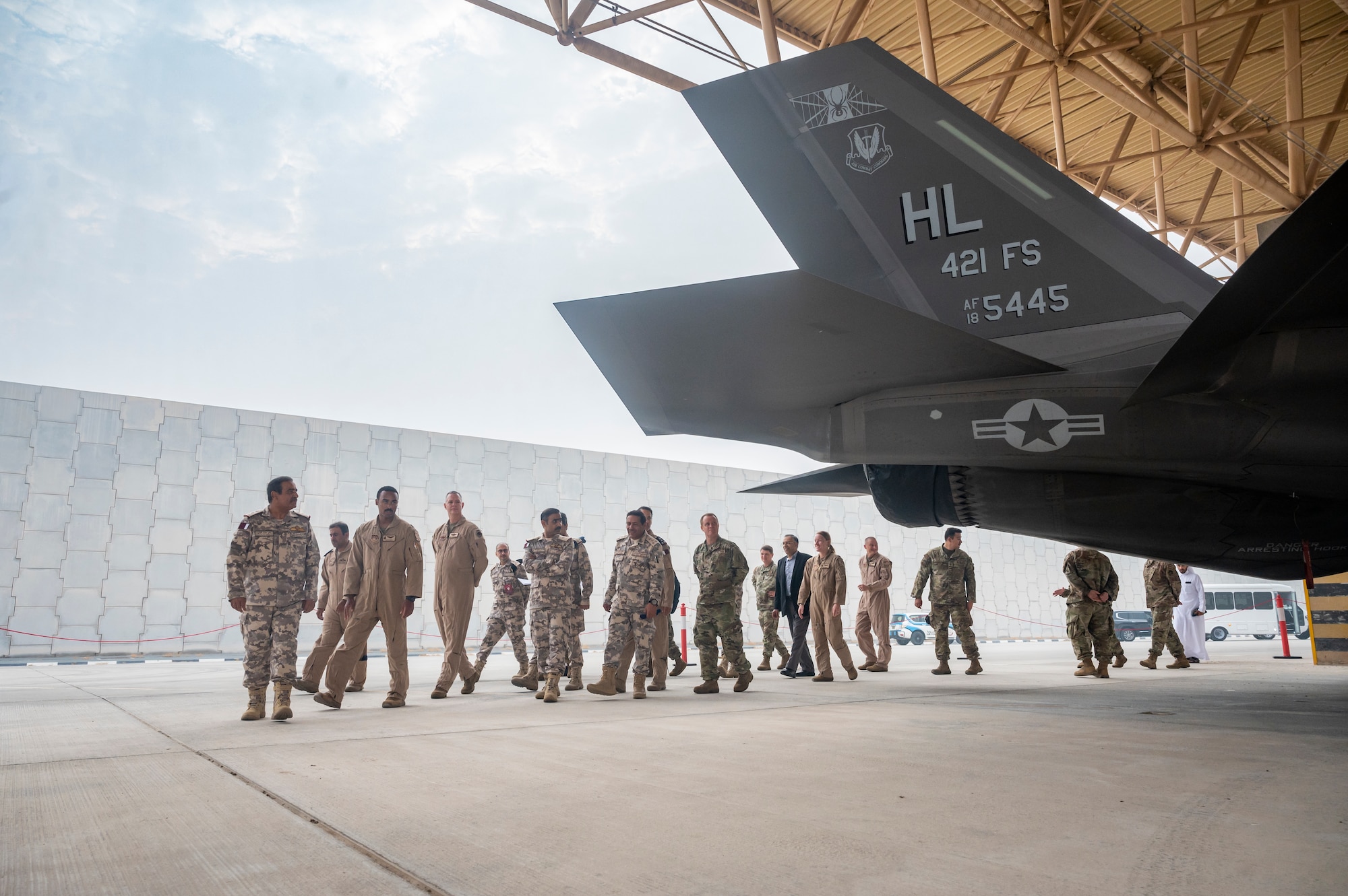 Group of military members walk around the back of an F-35