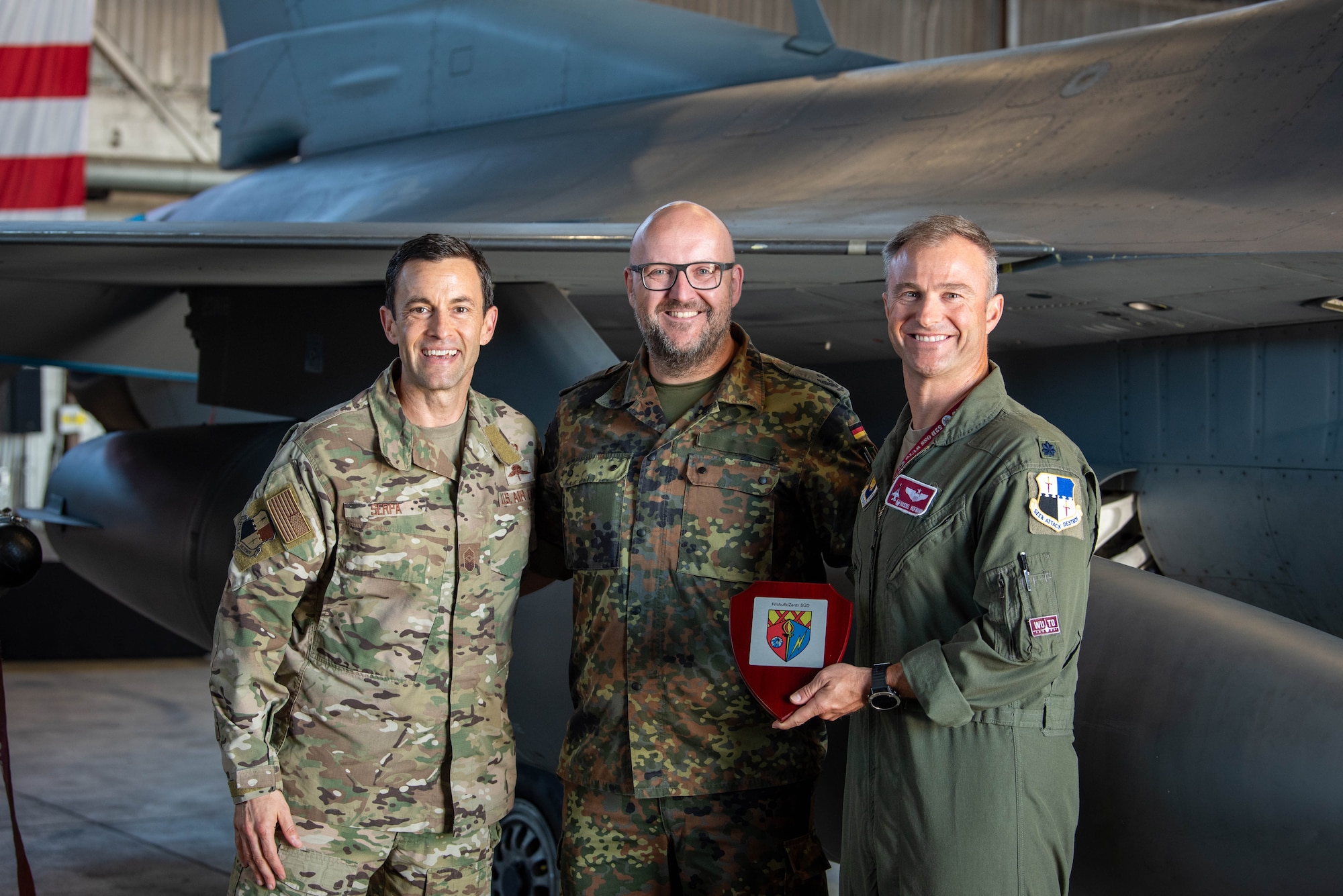 German Bundeswehr Lt. Col. Rafael Intek, Electronic Warfare Battalion 931, Electronic Reconnaissance Squadron commander (center), presents a plaque to U.S. Air Force Chief Master Sgt. Evan Serpa, 52nd Fighter Wing command chief (left), and Lt. Col. Nathaniel Hofmann, 52nd Operations Support Squadron commander (right), during a base tour at Spangdahlem Air Base, Germany, Sept. 6, 2023.