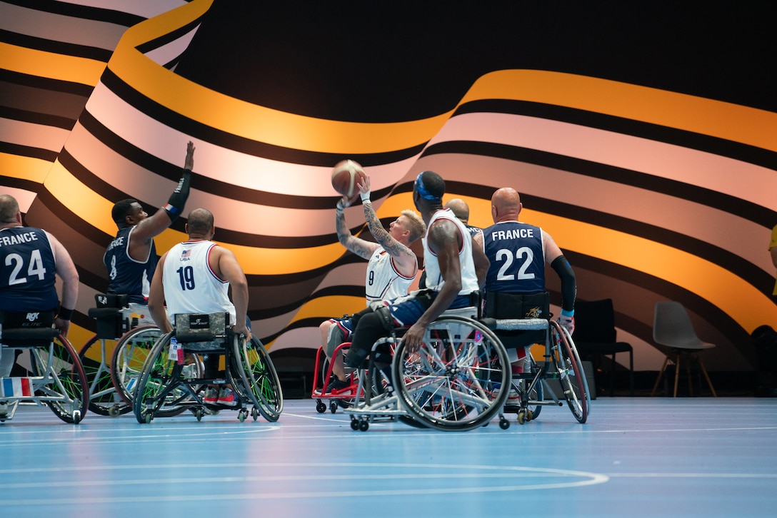 Athletes in wheelchairs play basketball.