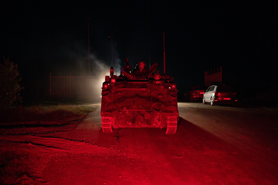 Soldiers ride in an armored tank at night during an exercise movement.