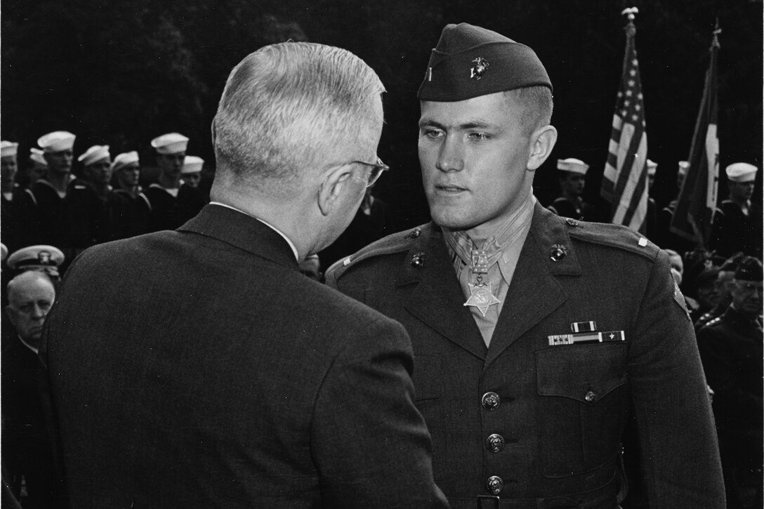 A person shakes the hand of a uniformed Marine.