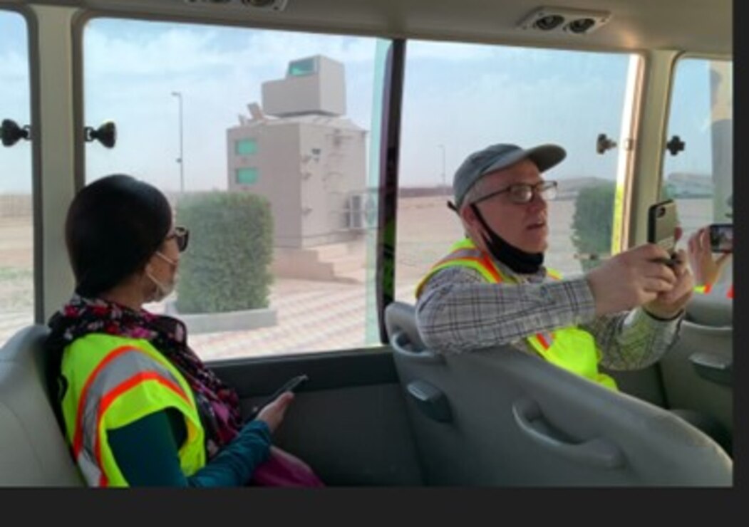 Two people in a car, man holding phone.