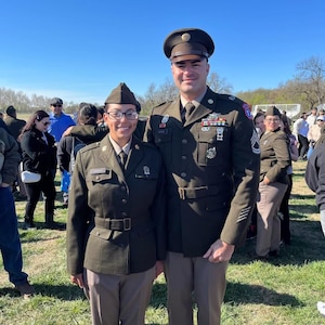 Male Soldier poses next to female Soldier outside at a graduation.