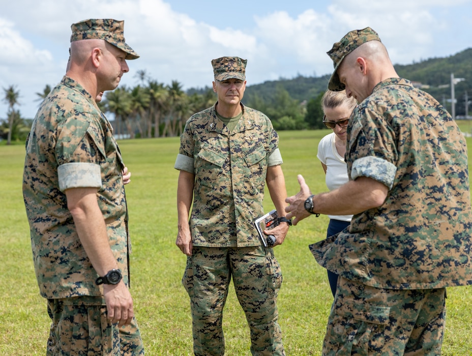 Three Marines in uniform standing outside reading off a paper.