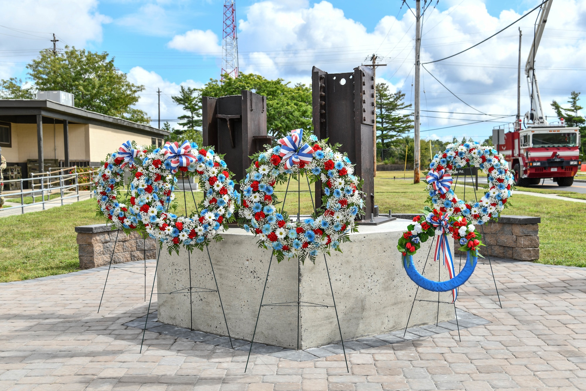 A photo of five commemorative floral wreaths standing in front of a 9/11 memorial