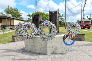 A photo of five commemorative floral wreaths standing in front of a 9/11 memorial