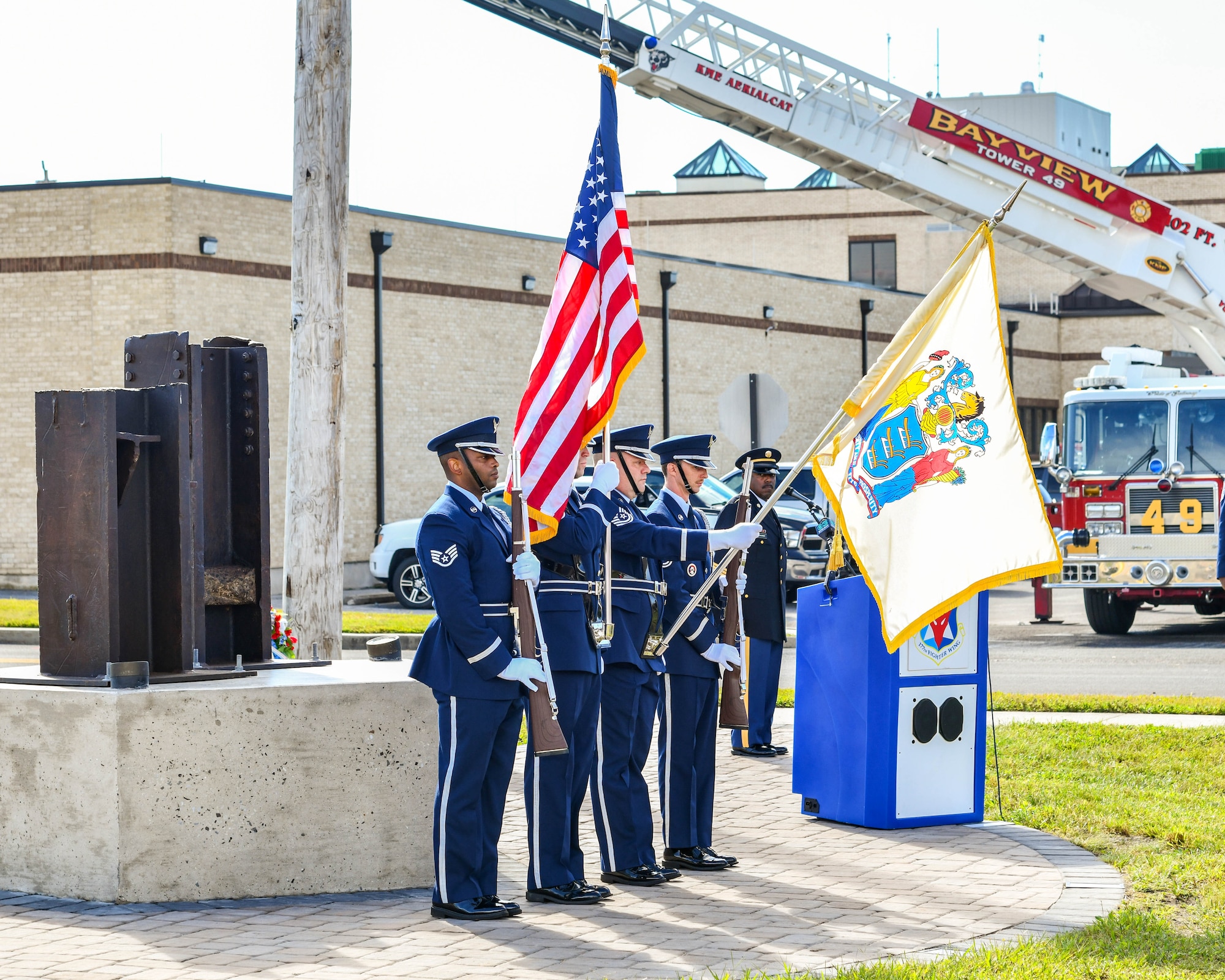 A photo of four Honor Guard Airmen presenting arms during a 9/11 memorial dedication ceremony.