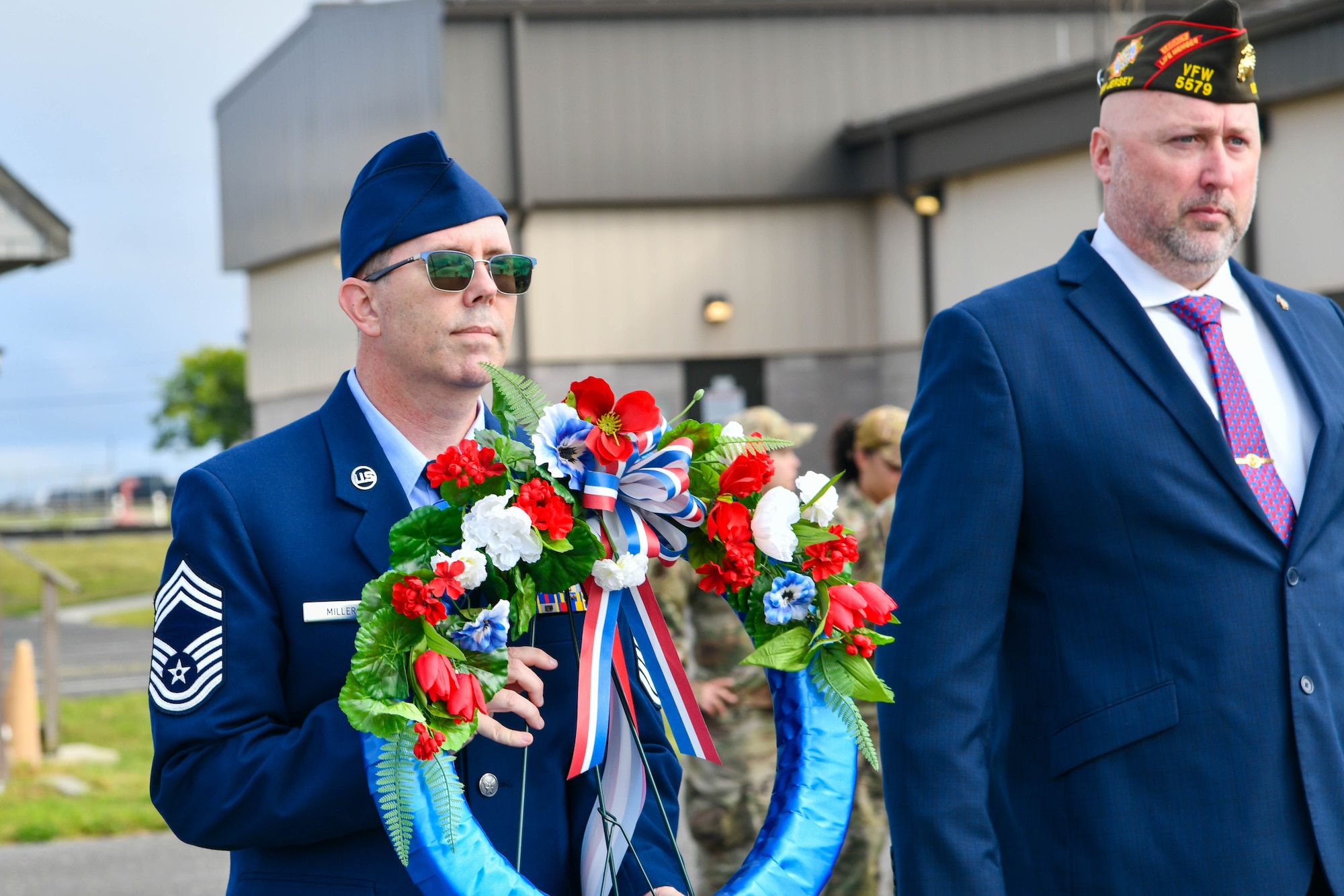 A photo of Chief Master Sgt. Wayne Miller holding a commemorative floral wreath.