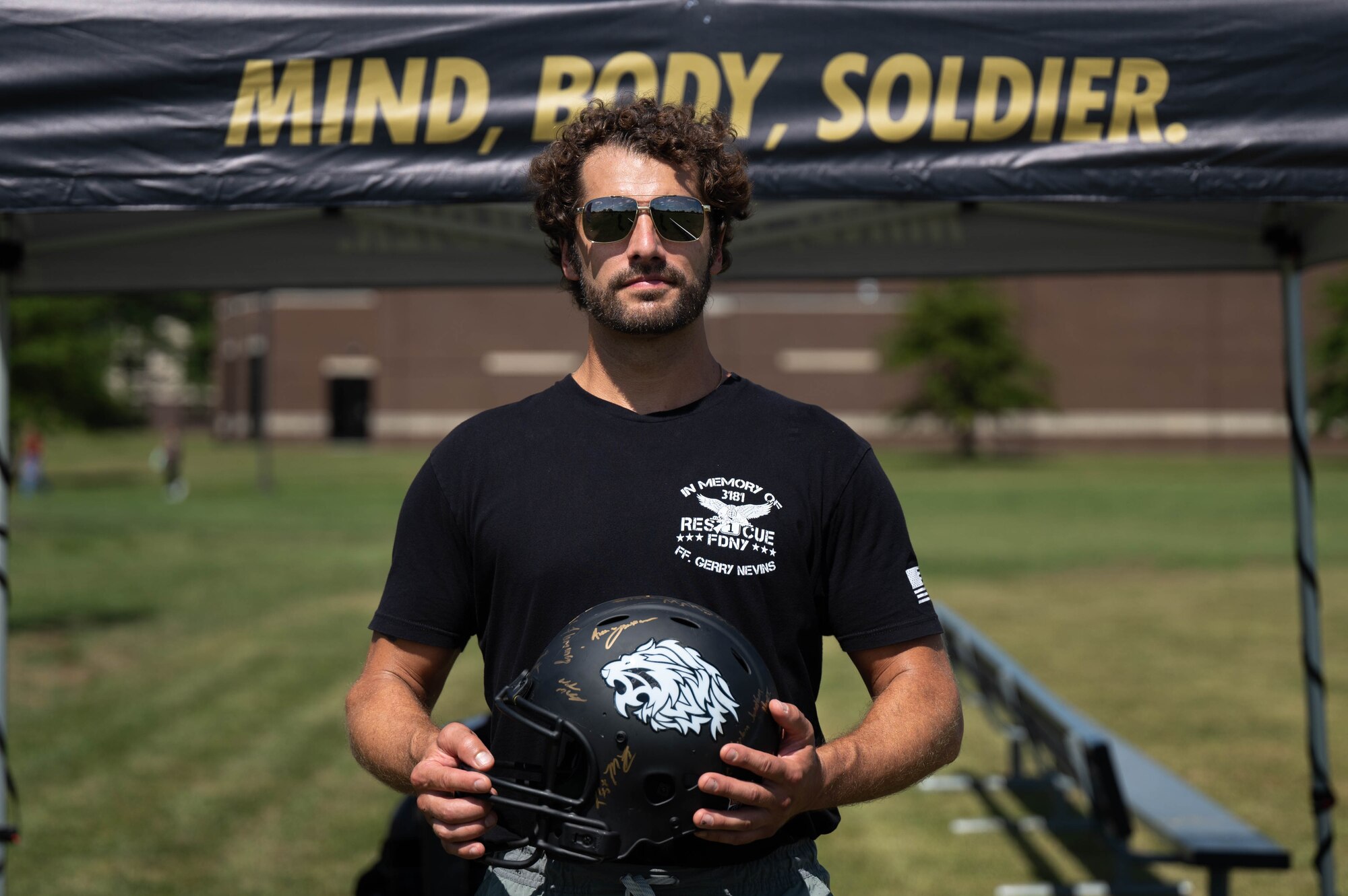 Man poses for a photo holding a football helmet