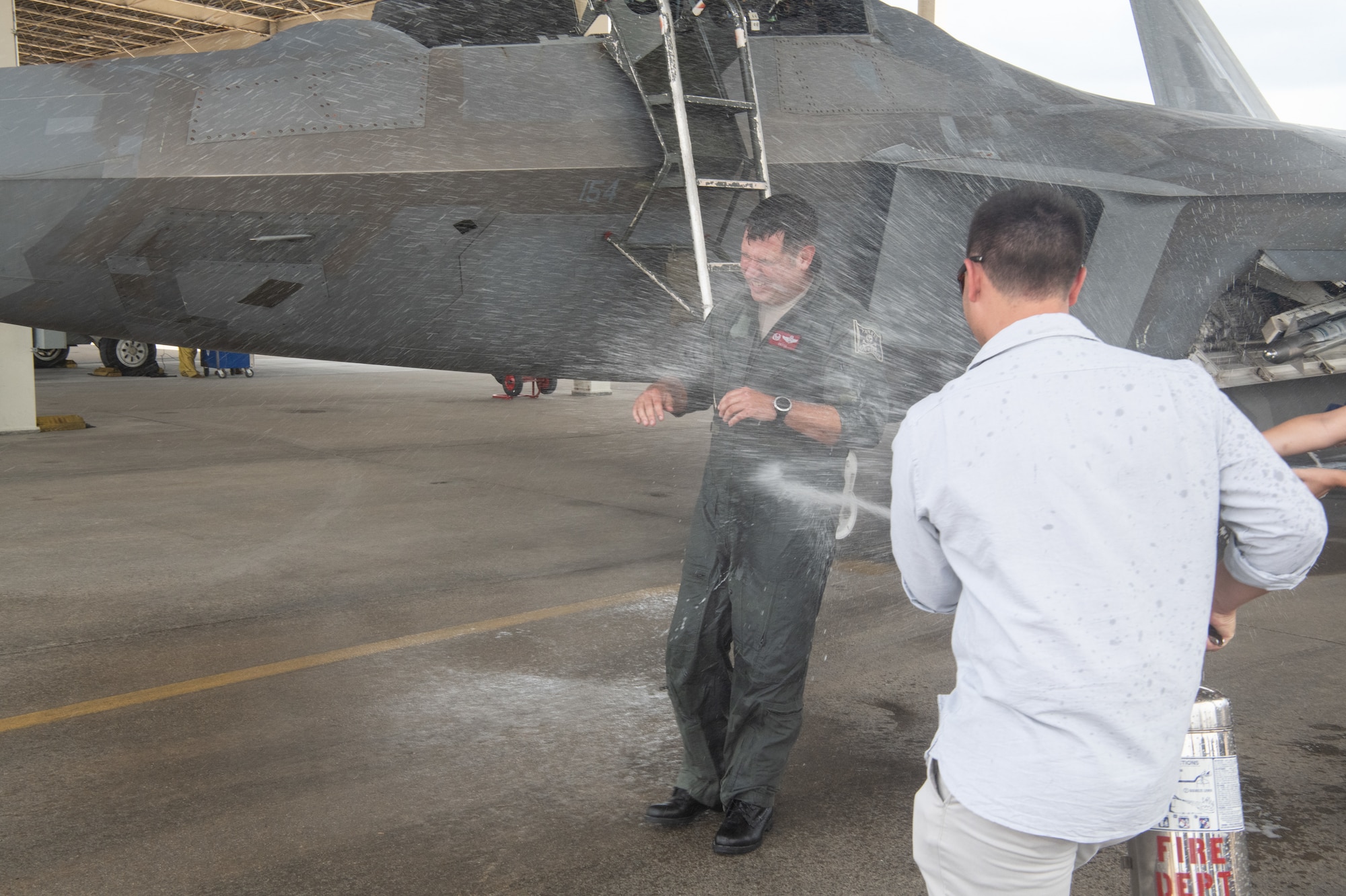 Pilot getting sprayed with water by son.