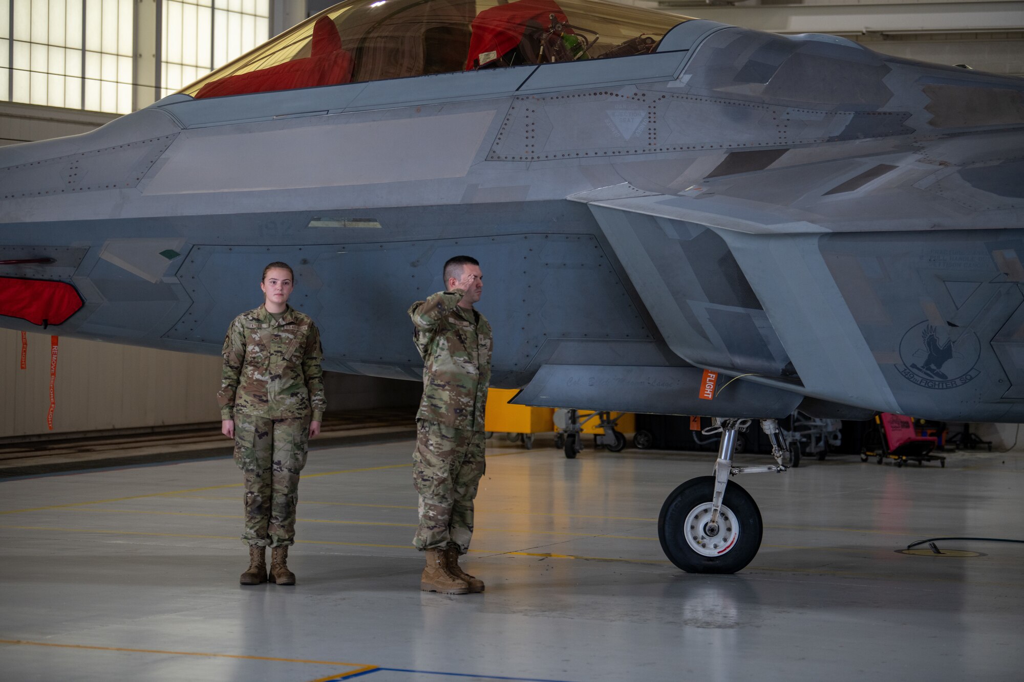 Two Airmen next to F-22, Airman on right saluting