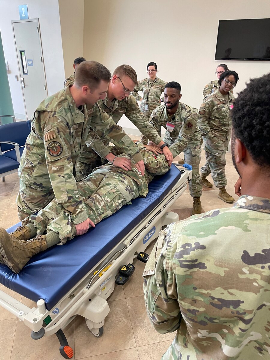 A photo of people in military uniforms moving a person on a hospital bed.