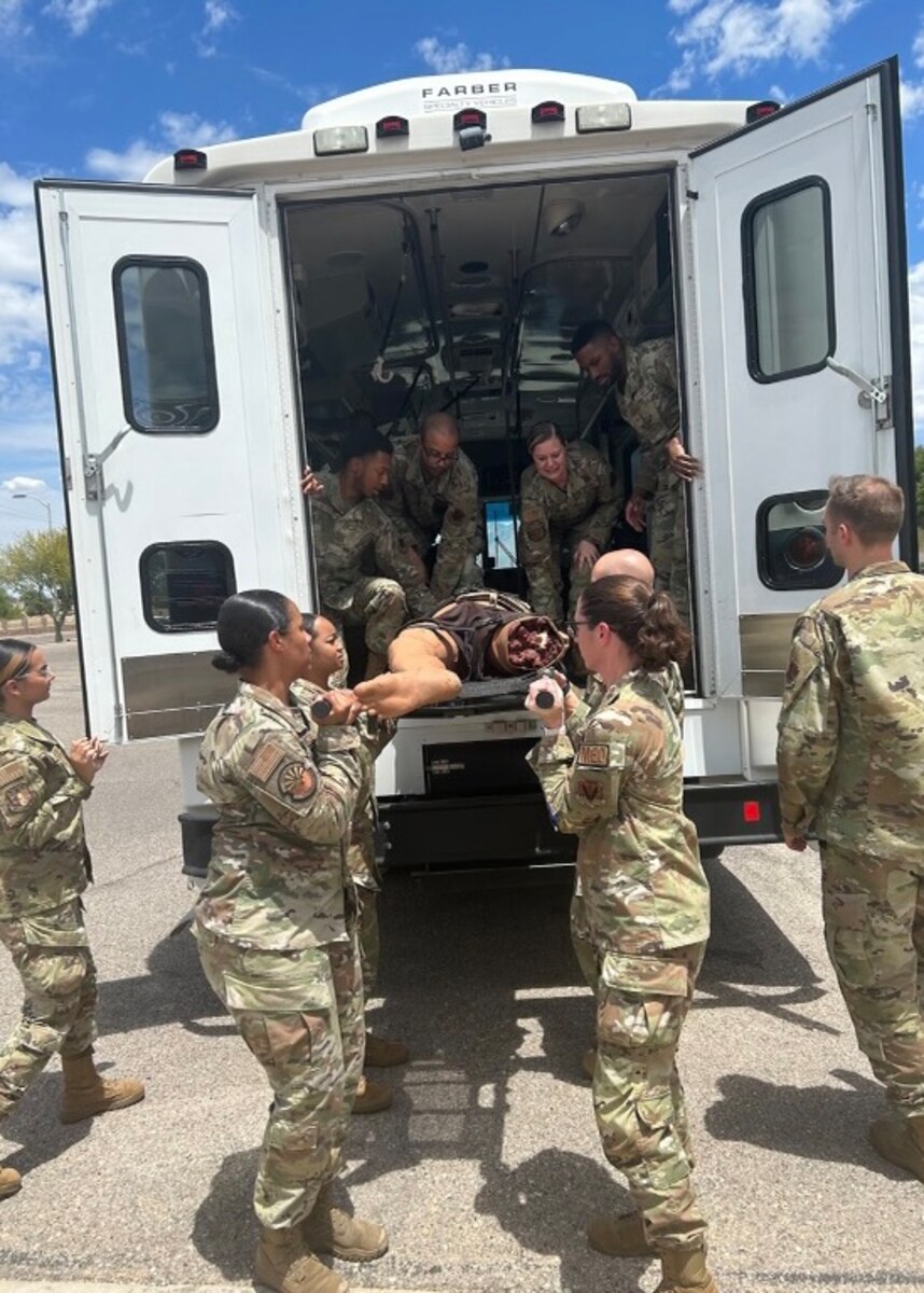 A photo of people in military uniforms unloading a stretcher from a bus.