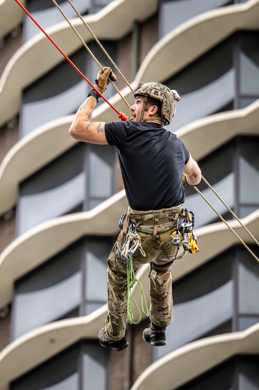 An airman scales a building.