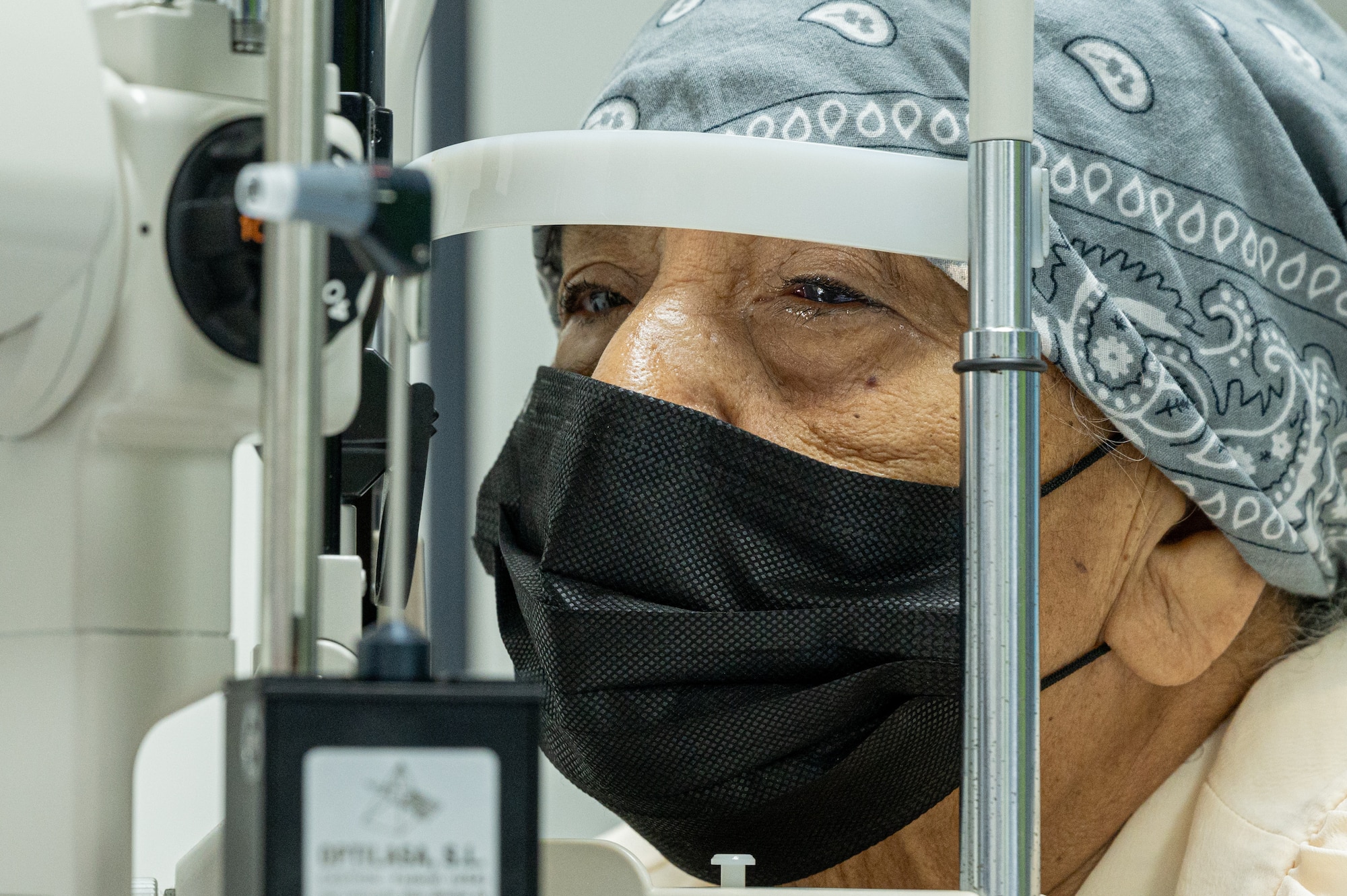 A patient sits in front of an autorefractor in the postoperative exam room to evaluate how her eye is healing after receiving manual small incision cataract surgery.