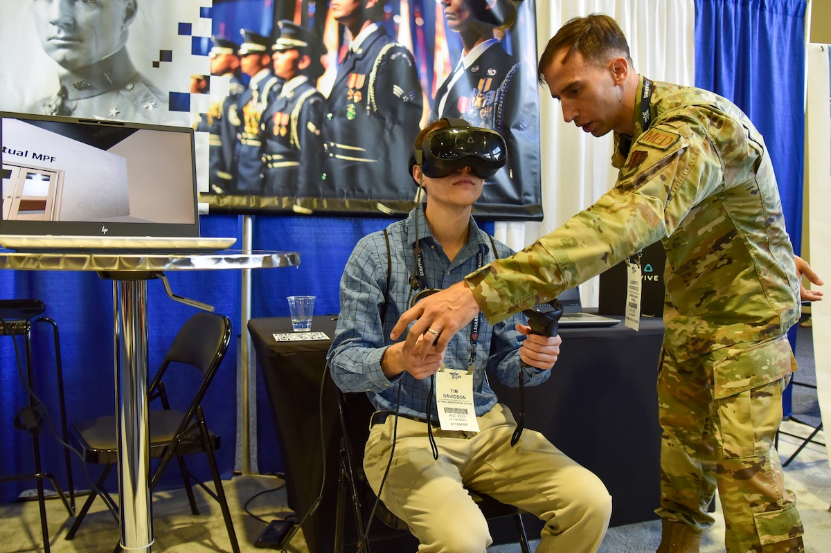 Tech. Sgt. Alberto Rodriguez, Spark Street booth exhibitor, gives a virtual reality demonstation to an Air, Space and Cyber Conference attendee at the Gaylord National Resort and Convention Center in National Harbor, Maryland, Sept. 12, 2023. Spark Street, a custom set of four booth spaces, showcased nearly 20 Spark Cells from around the world. Spark, an AFWERX division, connects Airmen and Guardian operators to commercial innovators and acquisition processes. (U.S. Air Force photo by Matthew Clouse)
