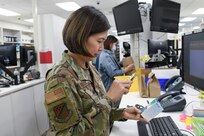 Maj. Nhon Nguyen using magnifying glass to view prescription box.