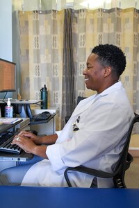 Lt. Col. LaToya Crocker sitting in chair and typing on computer.