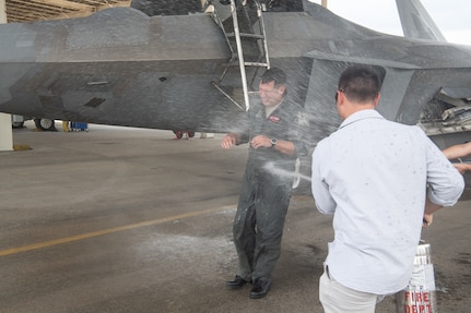 Pilot getting sprayed with water by son.