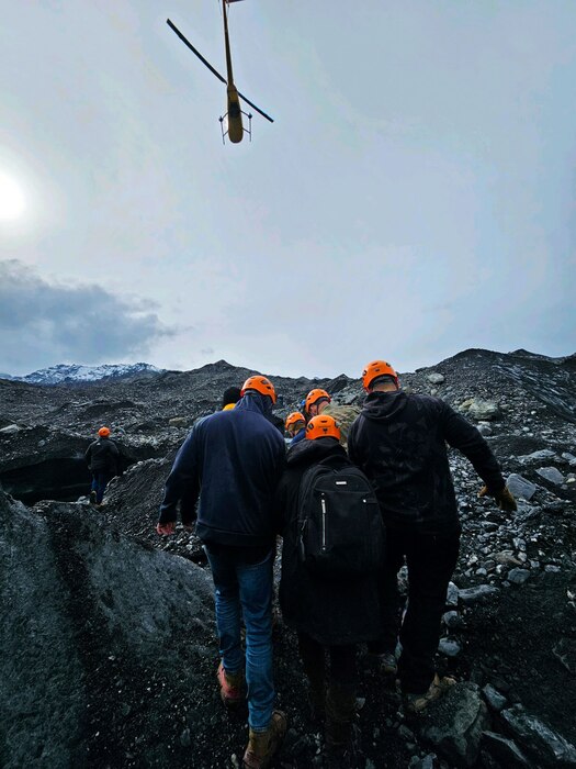 people carry a stretcher while helicopter flies above