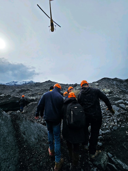 people carry a stretcher while helicopter flies above