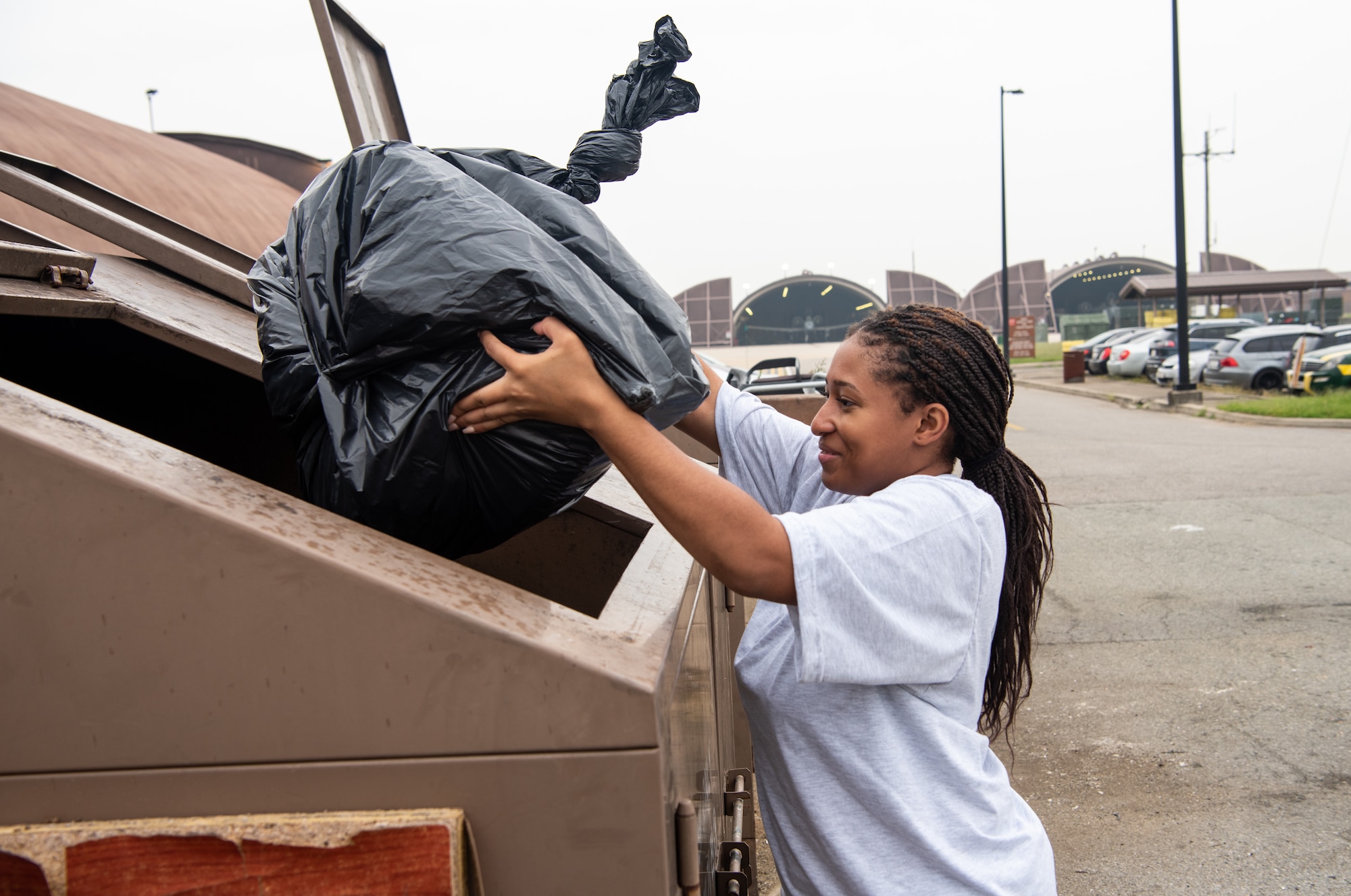 U.S. Air Force Airman 1st Class Sabrina Campbell, 51st Maintenance Squadron precision measurement equipment laboratory technician, throws trash into a dumpster during a base cleanup at Osan Air Base, Republic of Korea, Sept. 13, 2023. Base cleanups prolong the operational lifespan of the base by maintaining a safe and healthy environment. (U.S. Air Force photo by Airman 1st Class Chase Verzaal)
