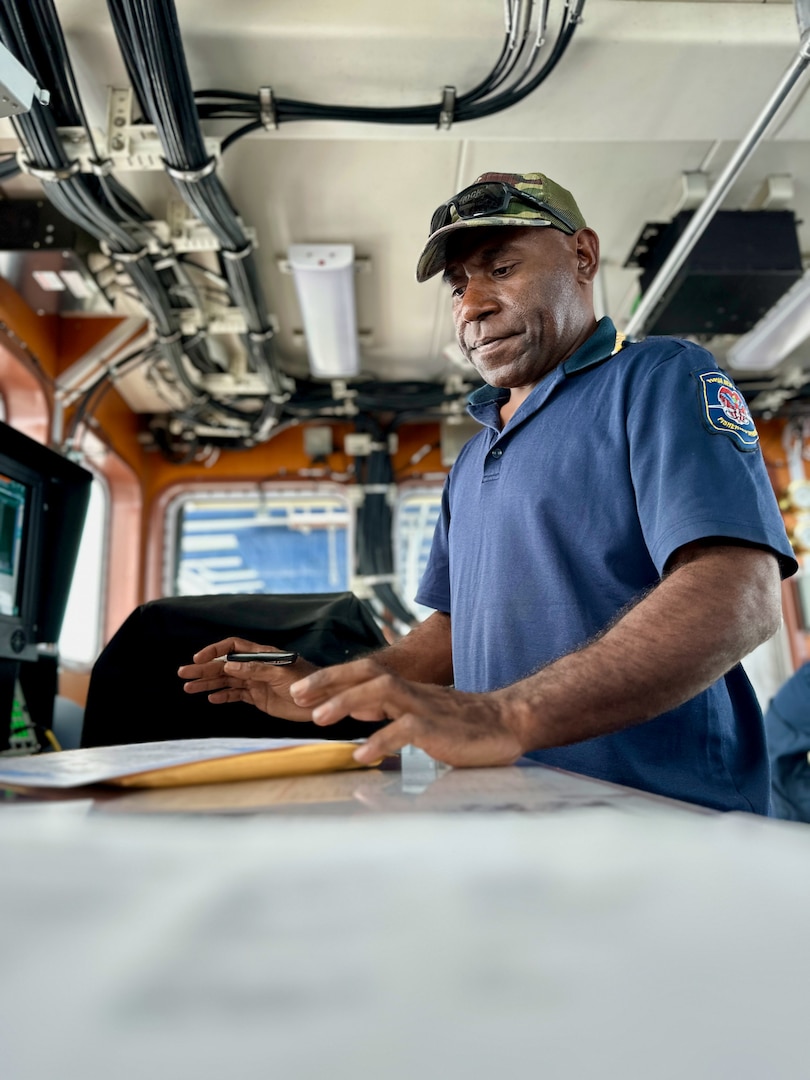 Rudolph Ihua of Papua New Guinea's National Fisheries Authority reviews information from a fishing vessel crew while aboard the USCGC Myrtle Hazard (WPC 1139) as the team conducts an observation report in 5 to 7-foot seas during a combined patrol on Aug. 26, 2023, in the Coral Sea off Papua New Guinea. The U.S. Coast Guard was in Papua New Guinea at the invitation of the PNG government to join their lead in maritime operations to combat illegal fishing and safeguard marine resources following the recent signing and ratification of a bilateral maritime law enforcement agreement between the United States and Papua New Guinea. (U.S. Coast Guard photo by Chief Warrant Officer Sara Muir)