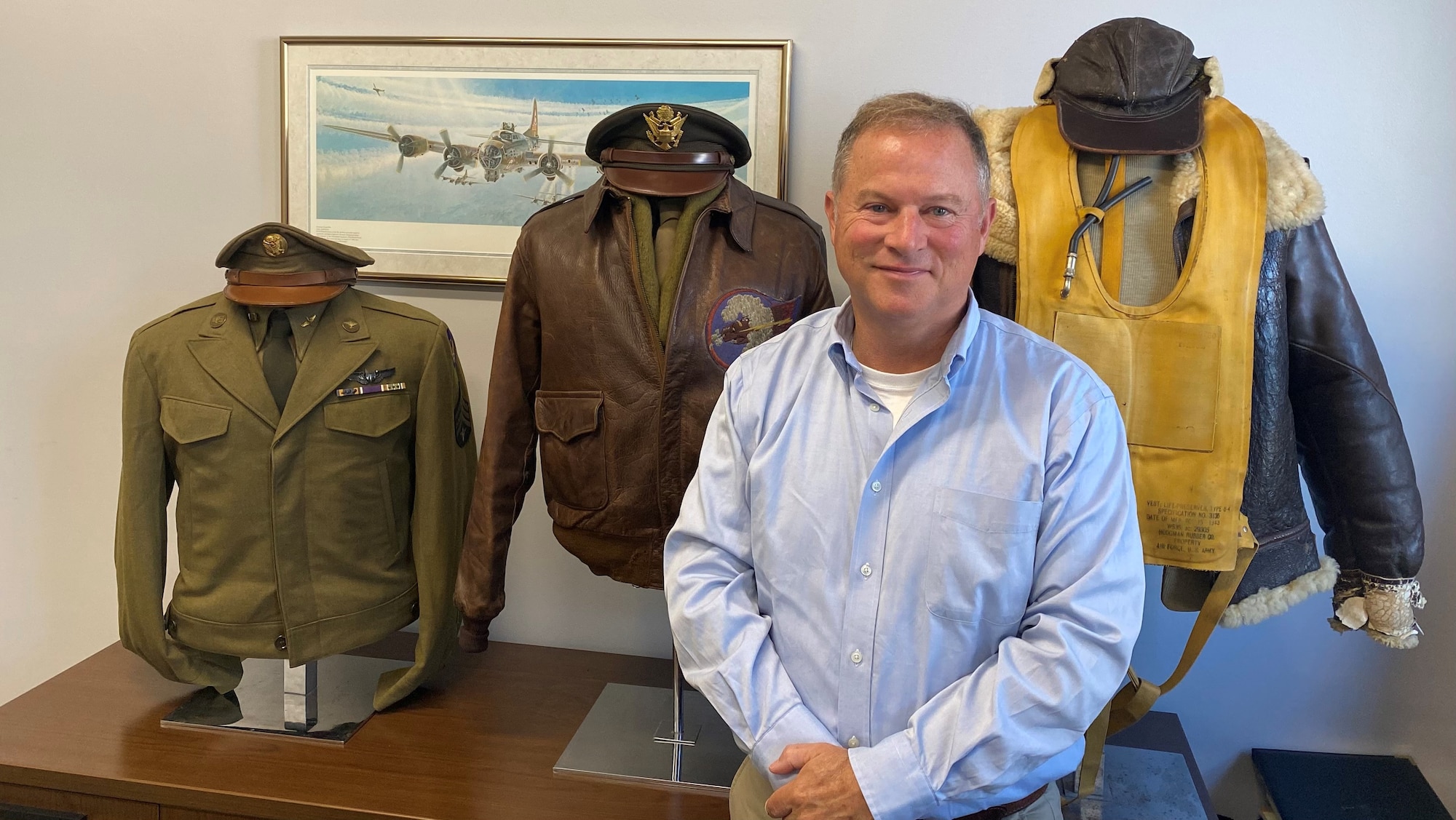Alan Brady standing in front of three busts adorned with vintage pilot uniforms dating back to World War II.