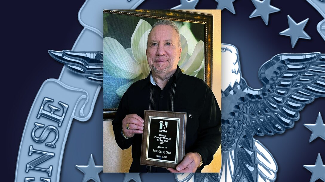 A man holds an award plaque.