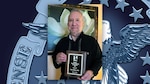 A man holds an award plaque.