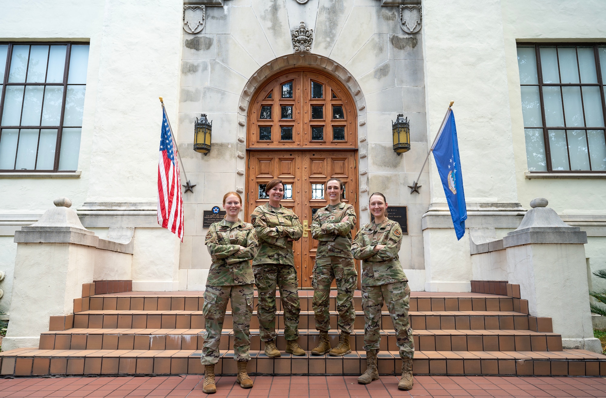 Four women in Air Force uniforms stand on the stairs in front of the building for the Air Education and Training Command at Kirtland Air Force Base, New Mexico.