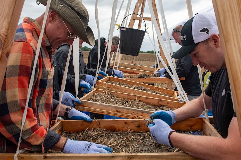 People examine excavated material in a screen.