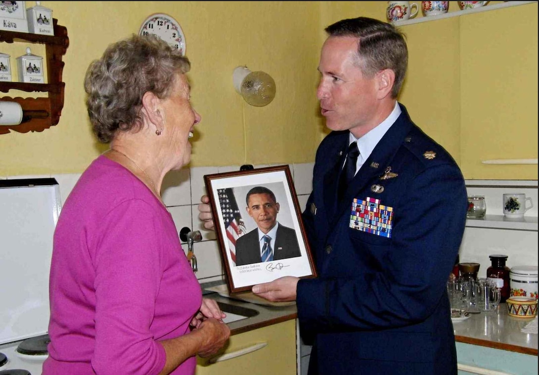 In this file photo from June 2012, Maj. John Williams presents a signed photo of President Barack Obama to Ms. Zdenka Sladkova, an 81-year-old Czech woman who, at age 14, witnessed the sacrifice of an American pilot who crashed and was killed while strafing a German convoy near her small village.