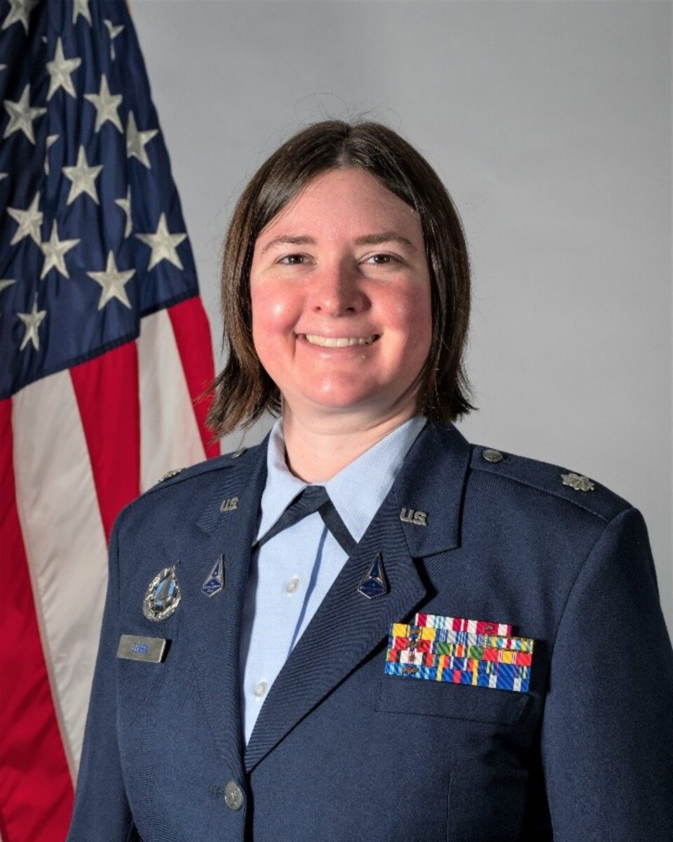 woman in uniform poses in front of American flag