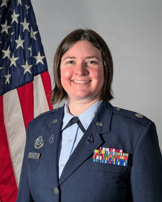 woman in uniform poses in front of American flag