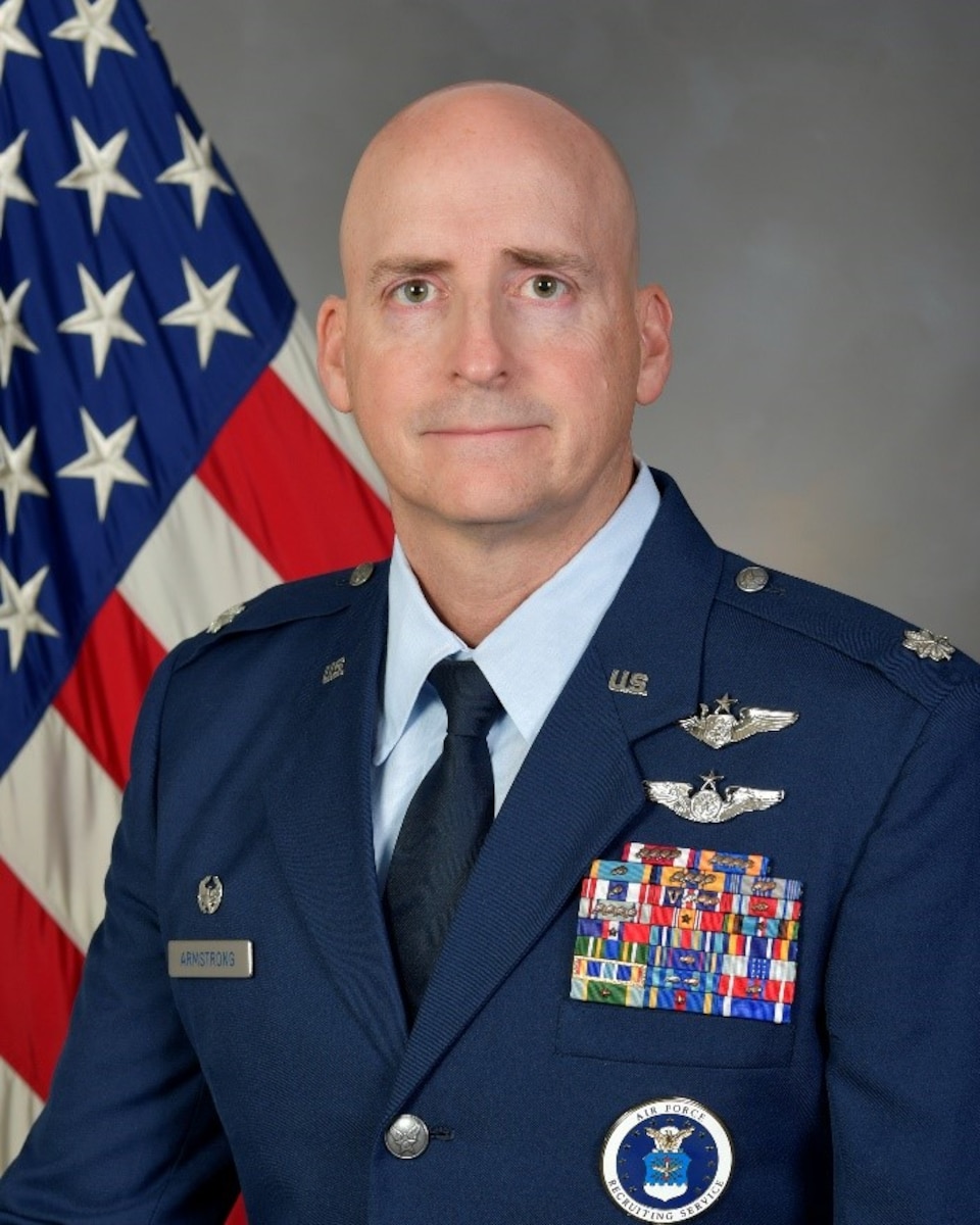 man in uniform poses in front of American flag