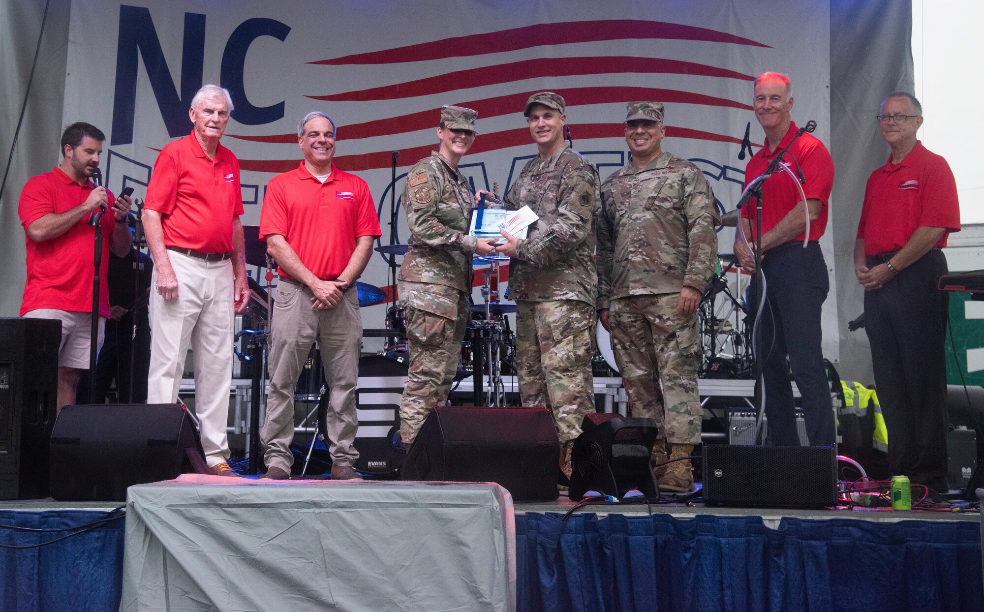 Col. Lucas Teel, center right, 4th Fighter Wing commander, and Chief Master Sgt. Martinez, second right, 4th FW command chief, recognize Senior Airman Destiny MacKinney, 4th Operations Support Squadron, for earning the Military Appreciation Award for the Airman category during NC Freedom Fest, at downtown Goldsboro, North Carolina, Sept. 9, 2023.
