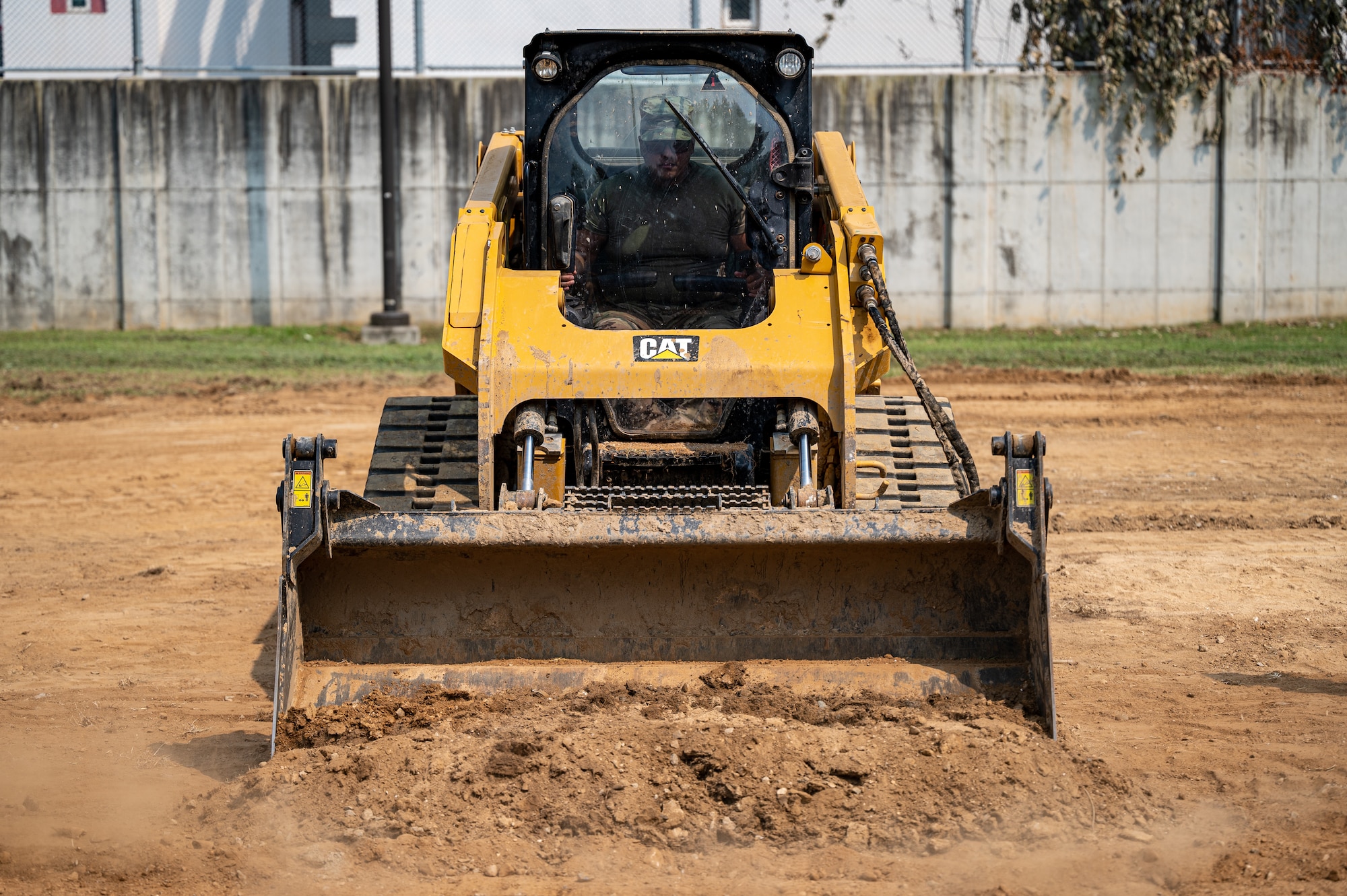 U.S. Air Force Senior Airman Jules Bocanegra, 51st Civil Engineer Squadron pavements and equipment journeyman, operates a compact track loader at Osan Air Base, Republic of Korea, Sept. 11, 2023. Bocanegra was tasked with a project to build a driveway for the 51st Security Forces Squadron's military working dog unit to provide a designated area for their vehicles. Pavements and construction Airmen focus on implementing projects that invest in Osan's current and future infrastructure needs. (U.S. Air Force photo by Staff Sgt. Thomas Sjoberg)
