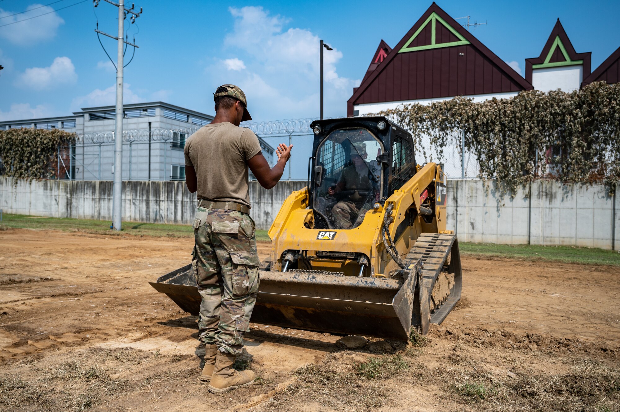 U.S. Air Force Senior Airman Abrien Dunn, left, guides Senior Airman Jules Bocanegra, both pavements and equipment journeymen assigned to the 51st Civil Engineer Squadron, during a construction project at Osan Air Base, Republic of Korea, Sept. 11, 2023. The 51st CES pavements and equipment Airmen play a vital role in maintaining the installation through conducting both preventative and corrective maintenance on roads, sidewalks, drainage systems and security fencing. Their work is crucial for the daily operations on base and for ensuring it remains in a well-sustained condition for current and future operations. (U.S. Air Force photo by Staff Sgt. Thomas Sjoberg)